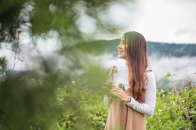 Attraktive asiatische Frau, die morgens ein Foto mit einer Retro-Filmkamera in der Natur auf dem Land macht