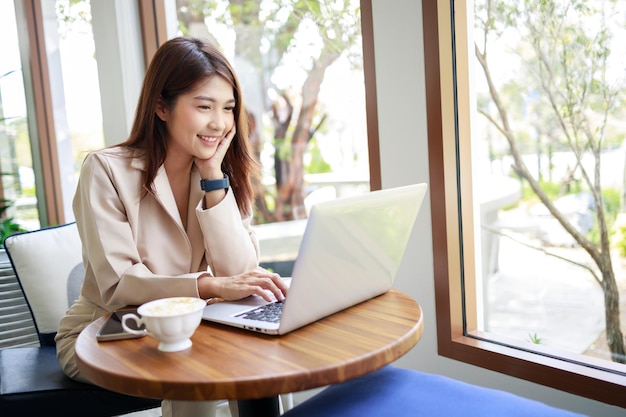 Attraktive asiatische Geschäftsfrau verwendet Laptop im Café Selbstbewusstes und intelligentes Geschäftskonzept