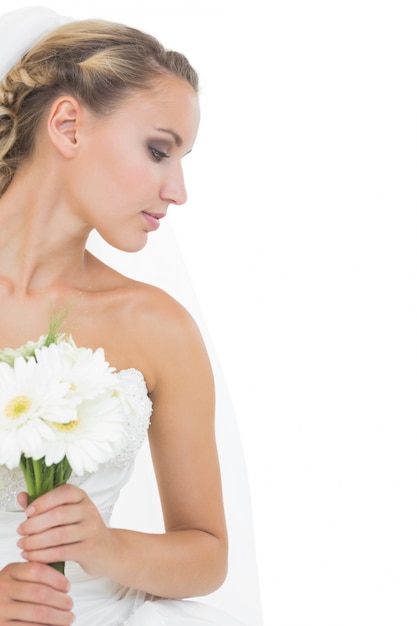 Attraktive blonde Braut, die einen Blumenstrauß anhält