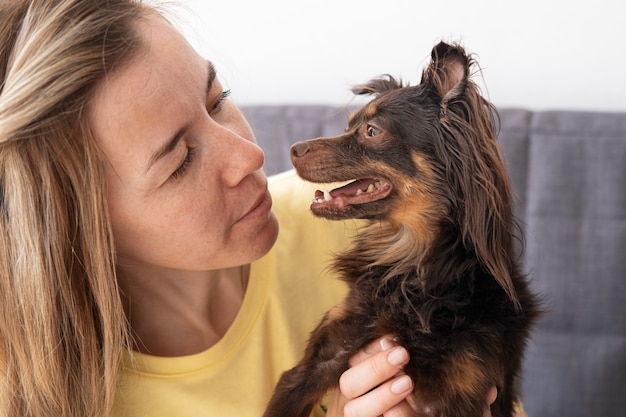 Attraktive blonde Frau mit lustigem braunem russischem Spielzeugterrier. einander ansehen. Haustierpflegekonzept.