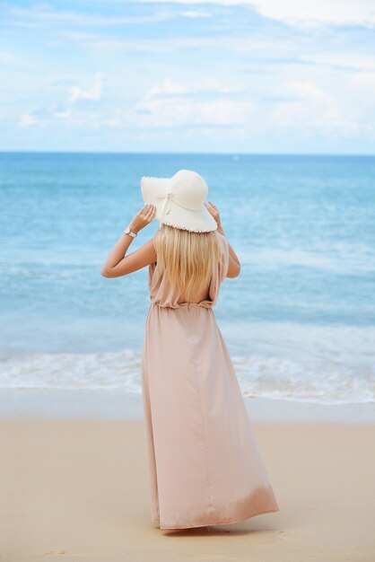 Attraktive blonde junge Frau steht am Strand