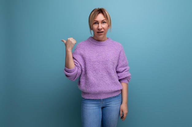 Attraktive blonde junge tausendjährige Frau im lässigen Look zeigt eine Geste zur Seite auf einem hellen