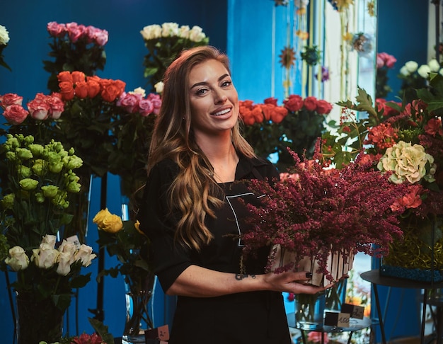 Attraktive Blumenladenbesitzerin posiert für Fotografen mit schönem Blumenstrauß in den Händen.