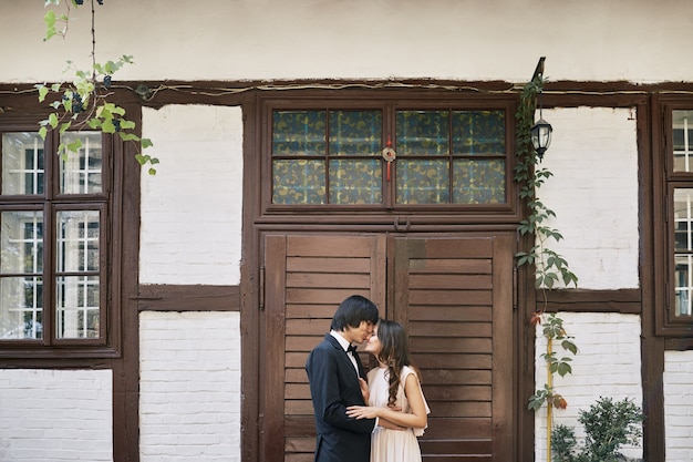 Attraktive Braut und Bräutigam, die nahe beieinander am alten Haushintergrund, Hochzeitsfoto, schönes Paar, Hochzeitstag, Porträt stehen.