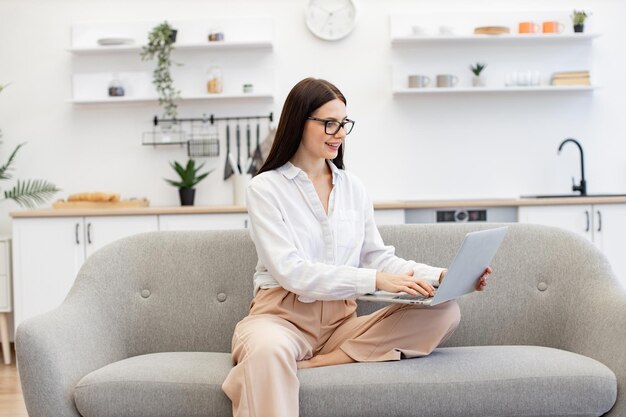 Attraktive brünette freiberufliche Frau arbeitet online, während sie zu Hause ist