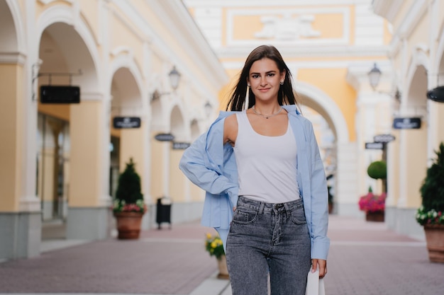 Attraktive brünette junge Frau, gekleidet in legerer Stellung vor verschwommenem Shopping-Mall-Look