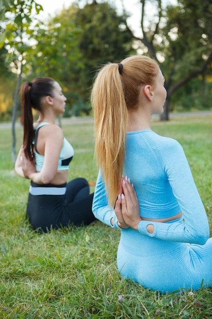 Attraktive fit Frauen, die zusammen Yoga im Park machen