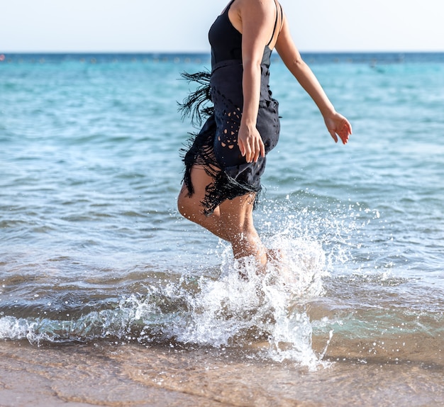 Attraktive Frau am Meer macht ihre Füße im Wasser nass.