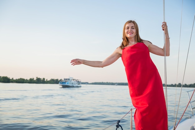 Attraktive Frau, die an einem sonnigen Sommertag am Fluss auf der Yacht posiert