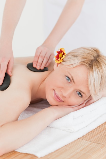 Attraktive Frau, die eine Massage mit heißen Steinen empfängt