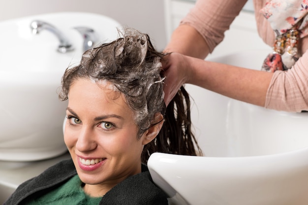 Attraktive Frau, die sich die Haare waschen lässt