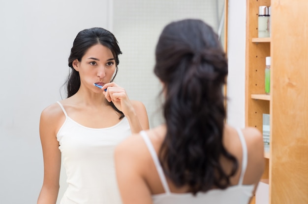 Attraktive Frau, die Zähne im Badezimmer putzt