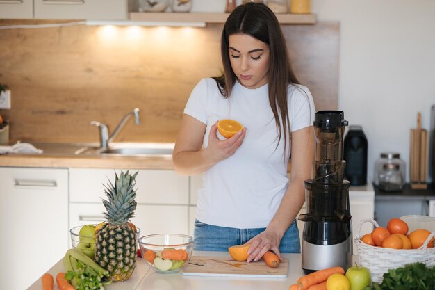 Attraktive Frau hält ein Stück Orangen in ihren Händen und schnuppt es einen vollen Tisch von Früchten und