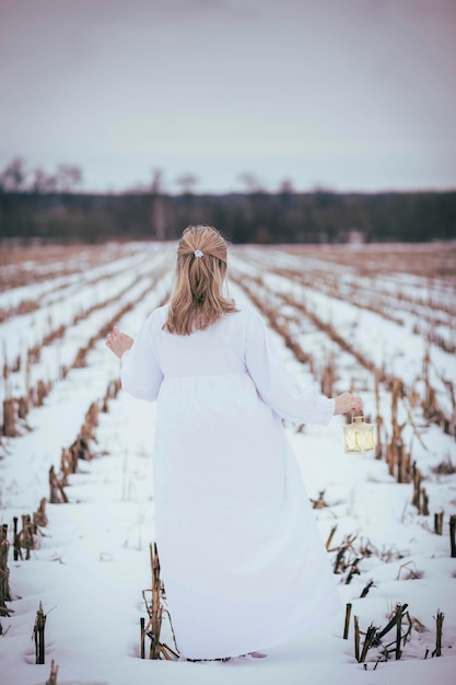 Attraktive Frau im Nachthemd auf dem Feld im Winter mit Handlampe