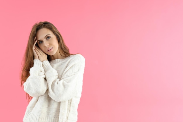Attraktive Frau im Pullover auf rosa Hintergrund