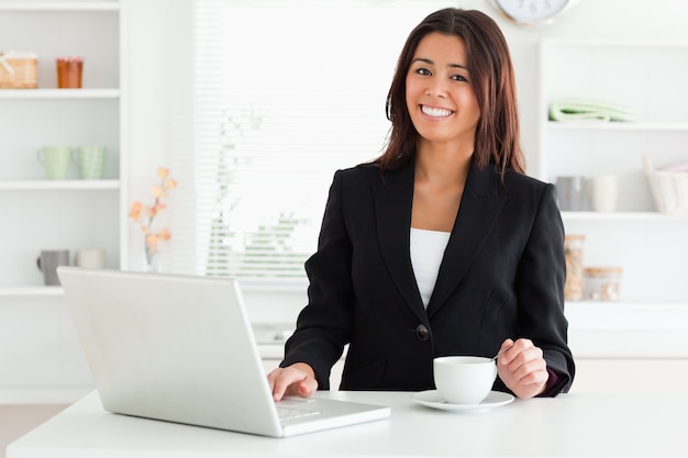 Attraktive Frau in der Klage einen Tasse Kaffee bei der Entspannung mit ihrem Laptop genießend