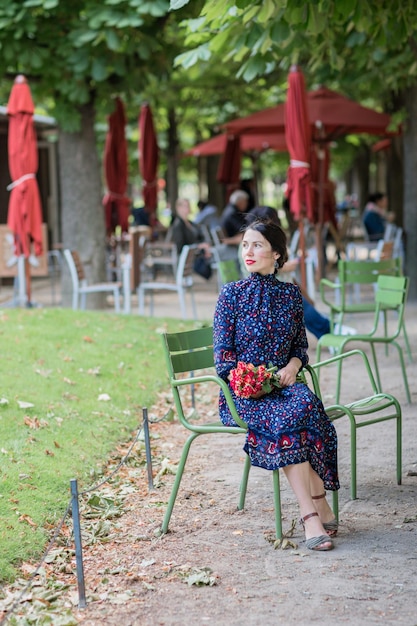 Attraktive Frau in einem blauen Kleid, die im Park sitzt