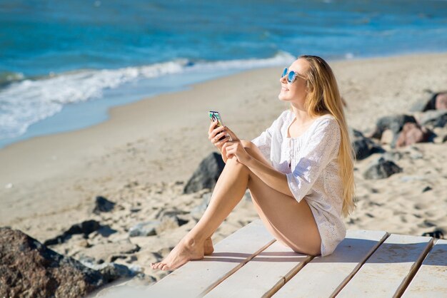 Attraktive Frau mit einem Telefon am Strand