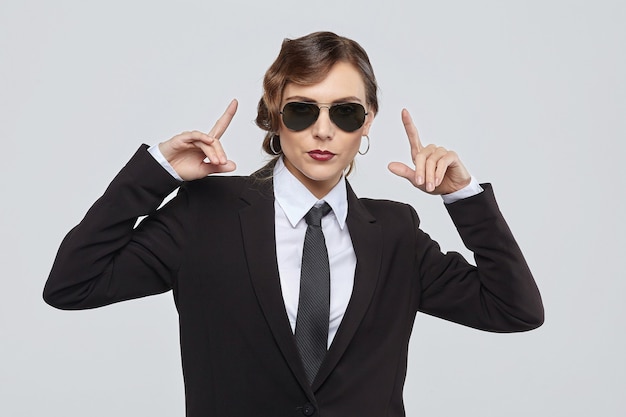 Attraktive Frau mit einer Retro-Frisur posiert in einem Herrenanzug und einer Sonnenbrille