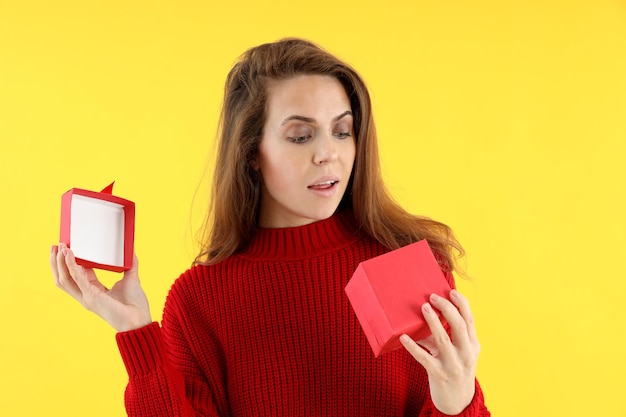 Attraktive Frau mit Geschenkbox auf gelbem Hintergrund