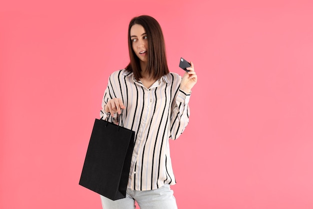 Attraktive Frau mit Shop-Tasche und Karte auf rosa Hintergrund