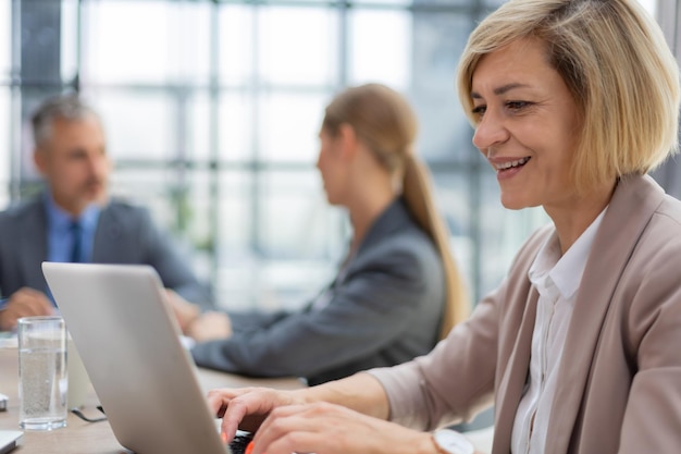 Attraktive Frau mittleren Alters, die mit Laptop im Büro arbeitet