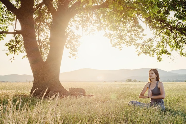 Attraktive Frau praktiziert im Sommer Yoga in der Natur