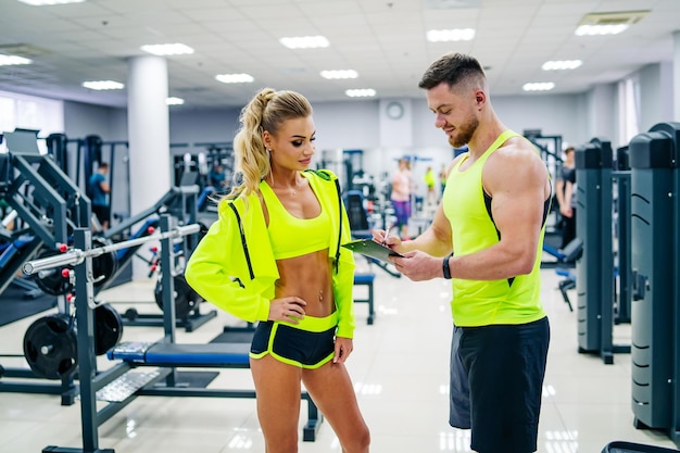 Attraktive Frau und gutaussehender Mann im modernen Fitnessstudio Junges Paar trainiert im Fitnessstudio