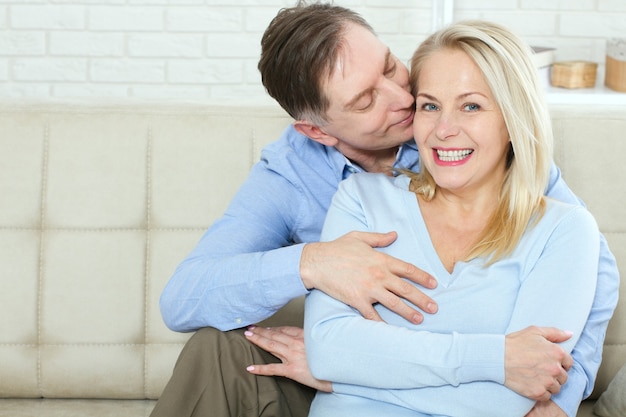 Attraktive Frau und Mann in einer Umarmung im Wohnzimmer.