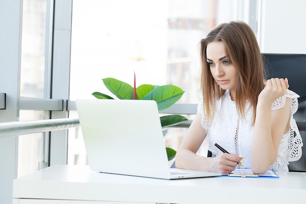 Attraktive Geschäftsfrau, die an ihrem Arbeitsplatz an Laptop arbeitet.