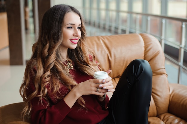 Attraktive Geschäftsfrau machen eine Kaffeepause auf dem Sofa.