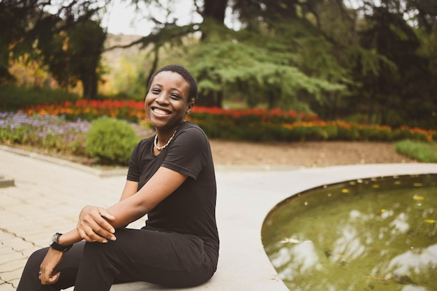 Foto attraktive glücklich lächelnde junge natürliche schönheit kurzhaarige afrikanische frau, die totales schwarzes trägt