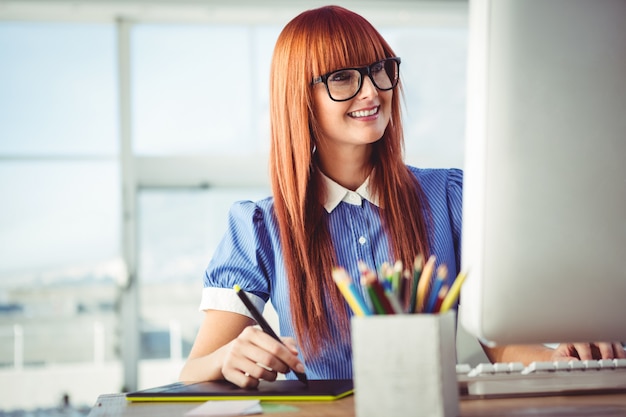 Attraktive Hippie-Frau, die Grafiktablette in ihrem Büro verwendet