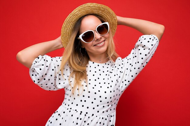 Attraktive junge blonde Frau, die jeden Tag stilvolle Kleidung und moderne Sonnenbrillen trägt, isoliert auf