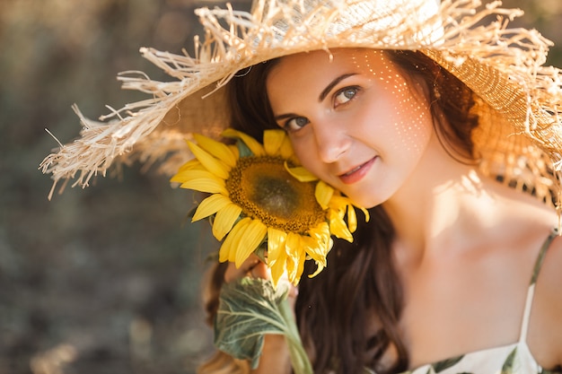 Attraktive junge Dame mit Sonnenblume. Schöne Frau draußen im Sommer.