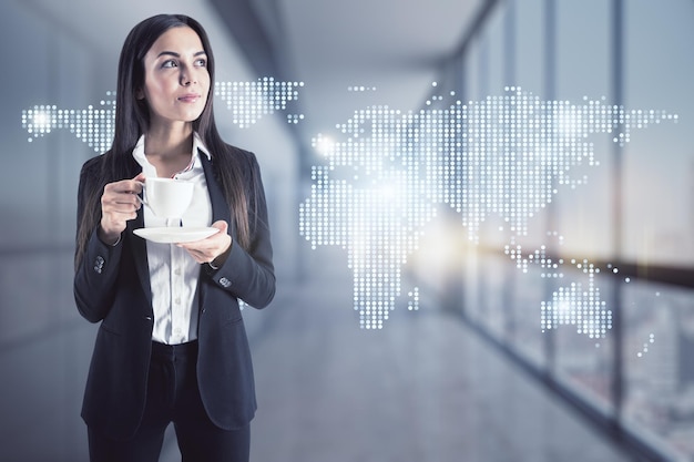 Attraktive junge europäische Geschäftsfrau mit Kaffeetasse steht im verschwommenen Bürointerieur mit glühendem Kartenhologramm Kommunikation und globales Big-Data-Konzept Doppelbelichtung
