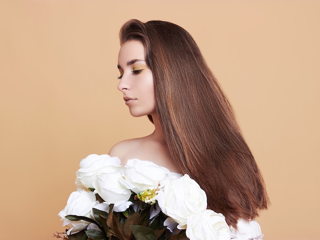 Attraktive, junge Frau auf weißem Hintergrund. Porträt eines schönen Mädchens mit einem Strauß weißer Blumen.