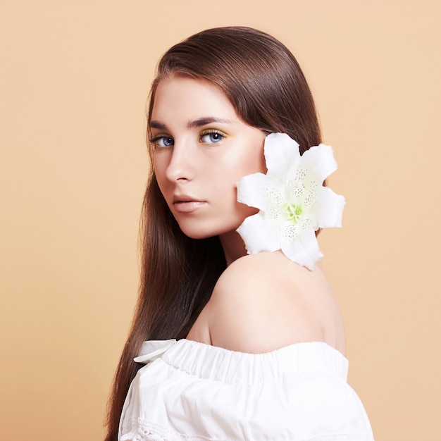 Attraktive, junge Frau auf weißem Hintergrund. Porträt eines schönen Mädchens mit einem Strauß weißer Blumen.