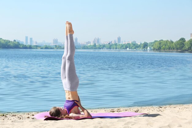 Attraktive junge Frau beim Yoga am Fluss