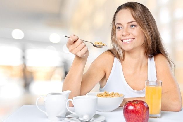 Attraktive junge Frau, die beim Frühstück Tee und Obst genießt