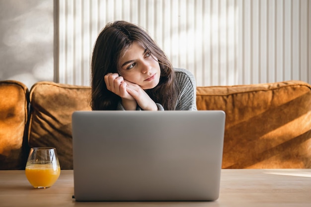 Attraktive junge Frau, die früh morgens an einem Laptop arbeitet