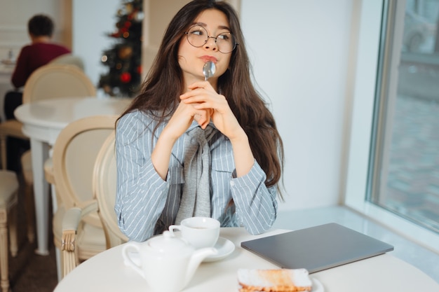 Attraktive junge Frau, die im Café entspannt und Tee trinkt