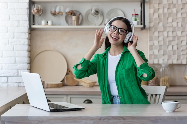 Attraktive junge Frau, die zu Hause mit Laptop arbeitet und Musik hört