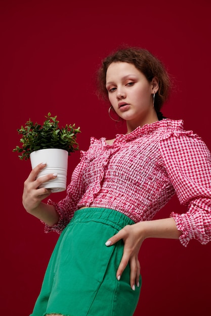 Attraktive junge Frau im Blumentopf der grünen Hosen, der die Nahaufnahme unverändert aufwirft