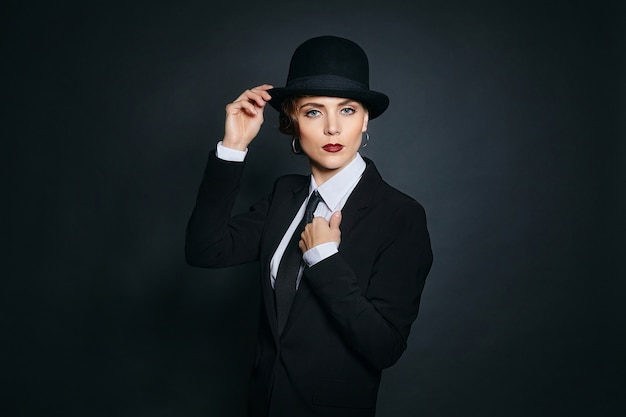 Attraktive junge Frau im Männeranzug und Fedora. Fotoshooting im Retro-Stil