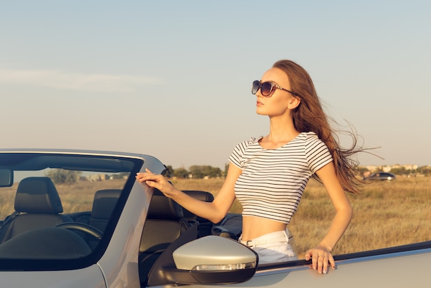 attraktive junge Frau in der Nähe eines Cabrio