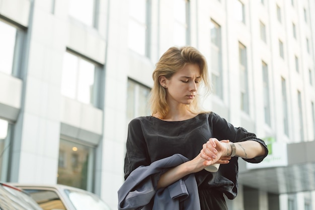 Attraktive junge Frau in Eile, die auf die Uhr an ihrem Handgelenk schaut und die Zeit überprüft