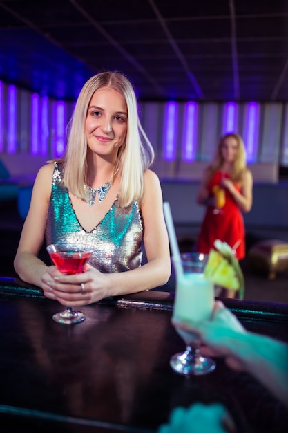 Attraktive junge Frau mit Cocktail im Nachtclub