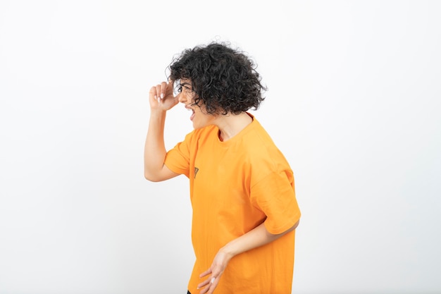 Attraktive junge Frau mit dem lockigen Haar im gelben T-Shirt, das aufwirft.