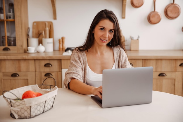 Attraktive junge Freiberuflerin, die Laptop verwendet und zu Hause arbeitet